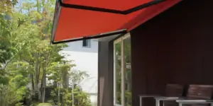 住宅のテラスに設置されたオレンジ色のオーニング（日よけ）。Together II生地を使用し、日差しを遮りながら屋外空間を快適に演出。